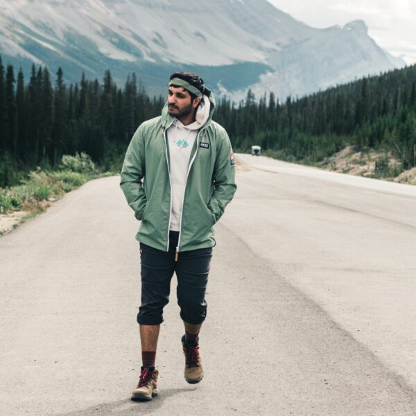 A hiker walking along the road in the shadow of a large mountain