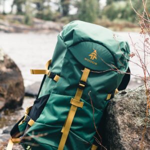 a photo of a green backpack resting against a rock on a creekbed