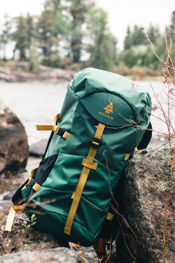 a photo of a green backpack resting against a rock on a creekbed