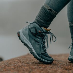 a photo of a hiker's feet wearing blueish green hiking shoes