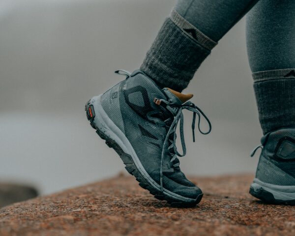 a photo of a hiker's feet wearing blueish green hiking shoes