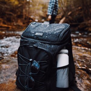 a photo of a backpack in the foreground with a hiker standing in the background