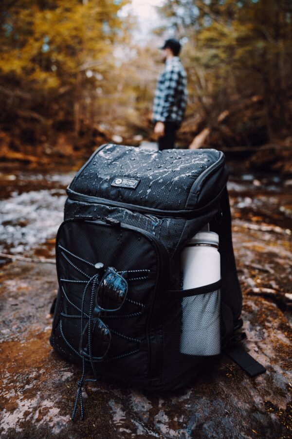 a photo of a backpack in the foreground with a hiker standing in the background