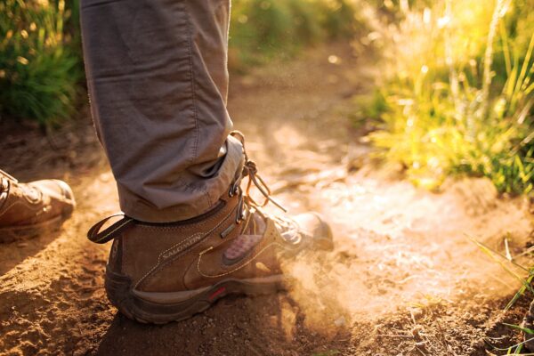 a photo of a hiker's feet wearing brown boots on a dirt path