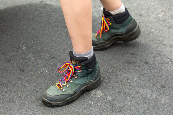 a photo of a hiker's feet wearing green boots standing on asphalt