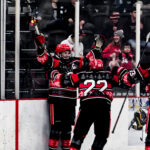 Ice Dawgs' captain Cameron Campbell celebrates a goal behind the net with his teammates.