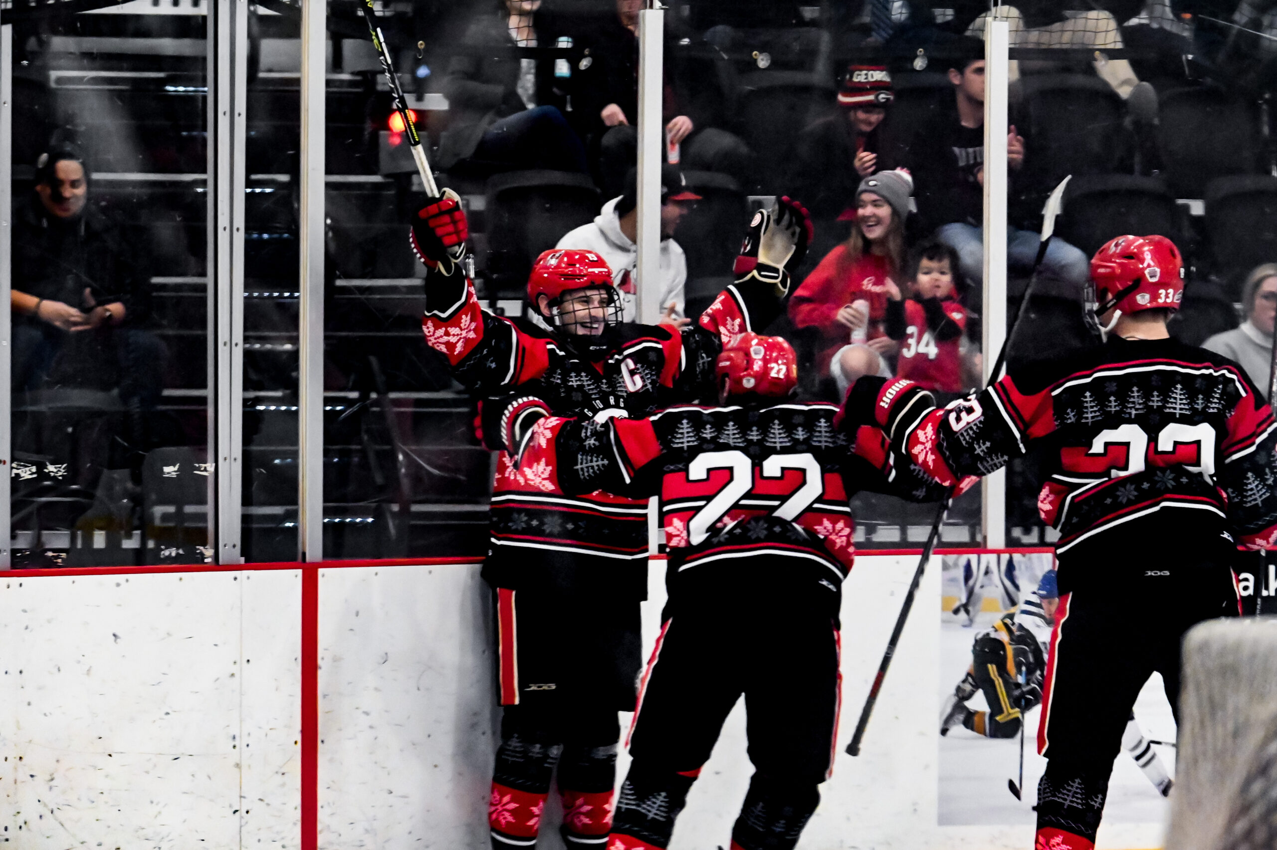 Ice Dawgs' captain Cameron Campbell celebrates a goal behind the net with his teammates.